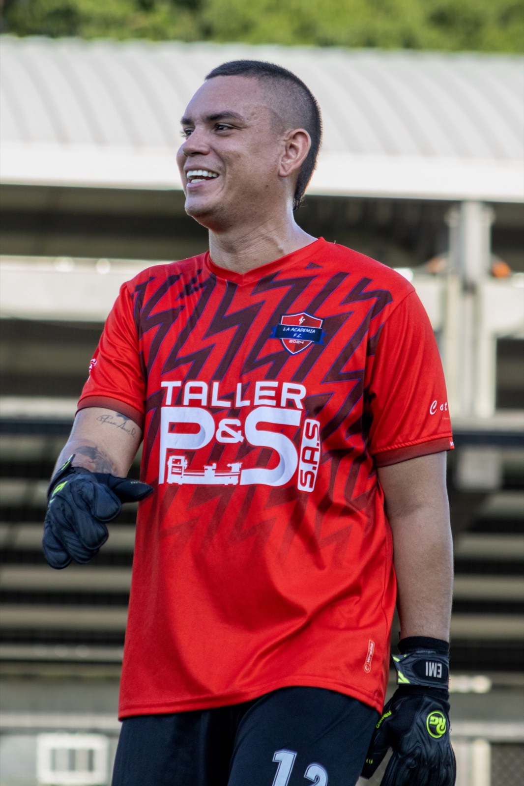Jugador adulto de La Academia F.C. sonriendo con su uniforme rojo