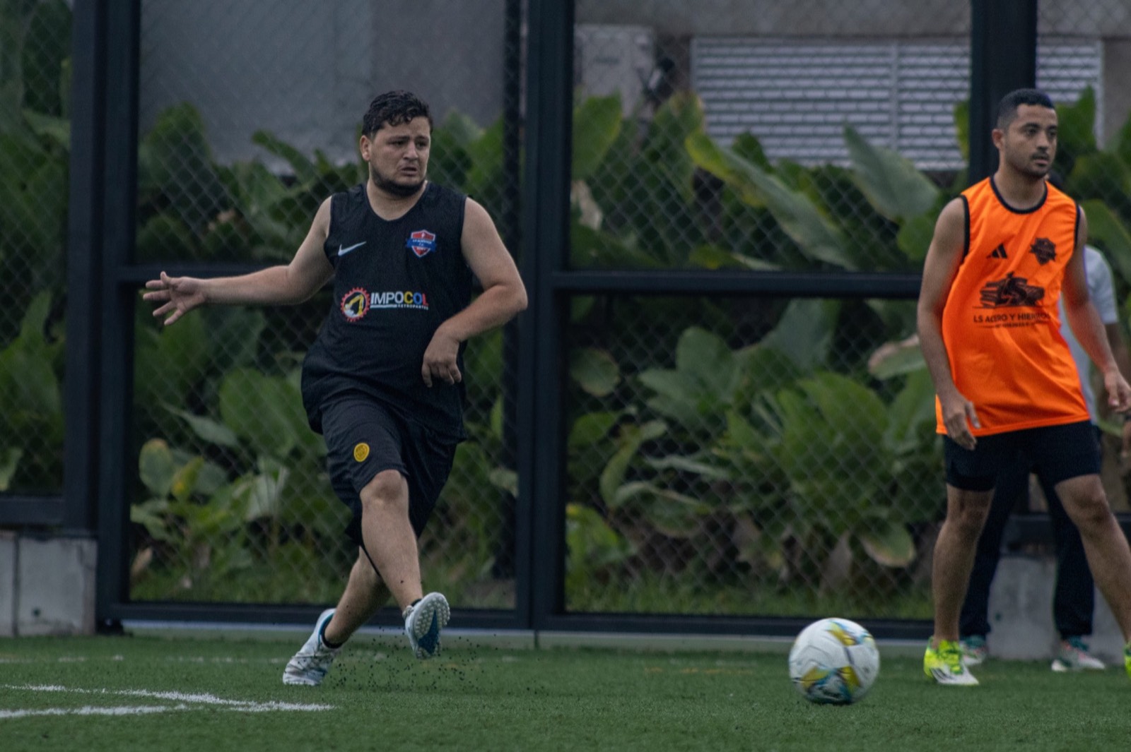 Dos jugadores adultos corriendo por el balón
